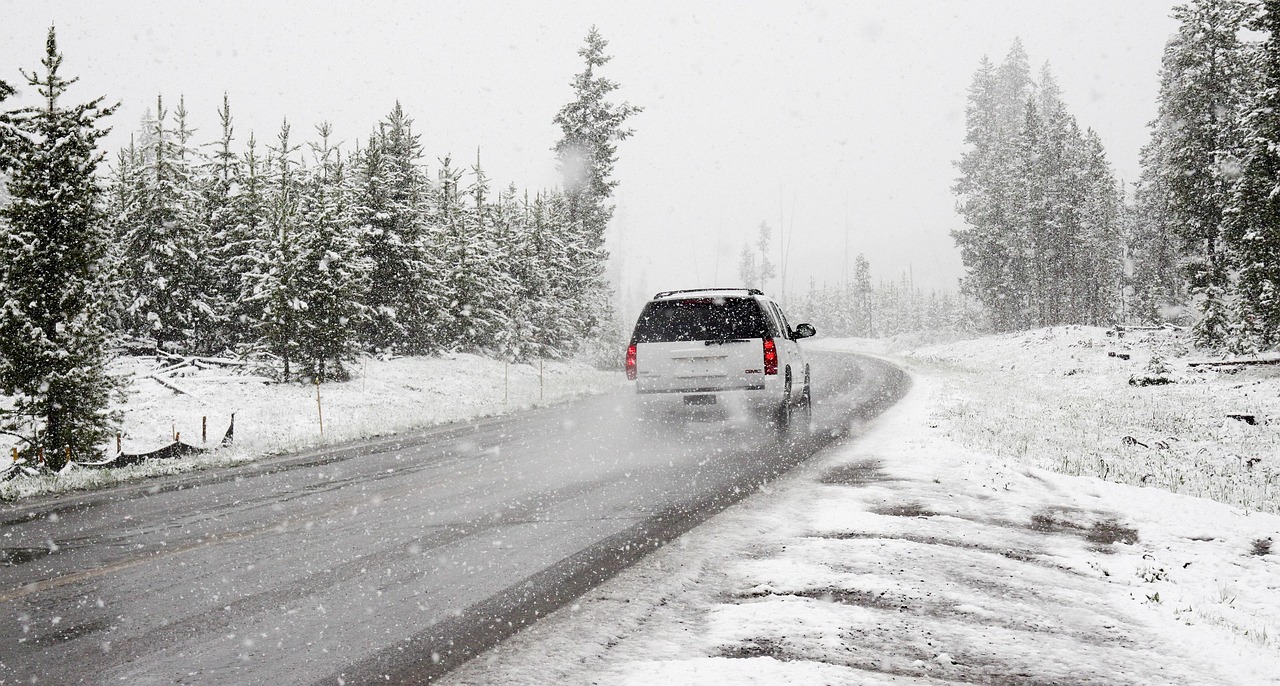 Car driving on a snow-covered road through pine trees